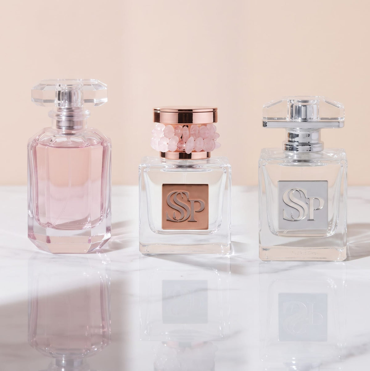 Sacred Pause, Lumière Soleil and Aura Noir bottles side by side on white marble