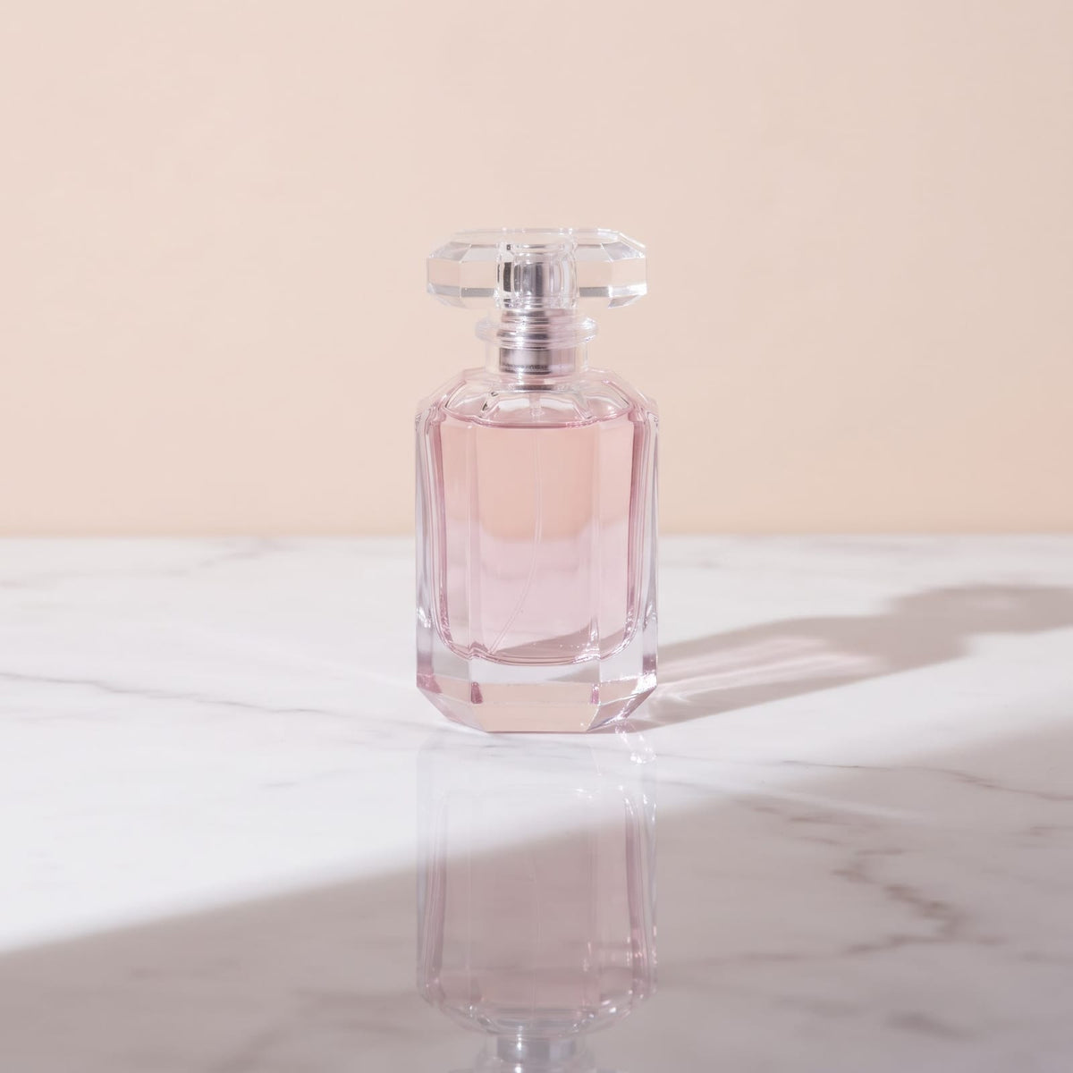 Sacred Pause Extrait de Parfum, faceted pink glass bottle with a crystal cap on white marble