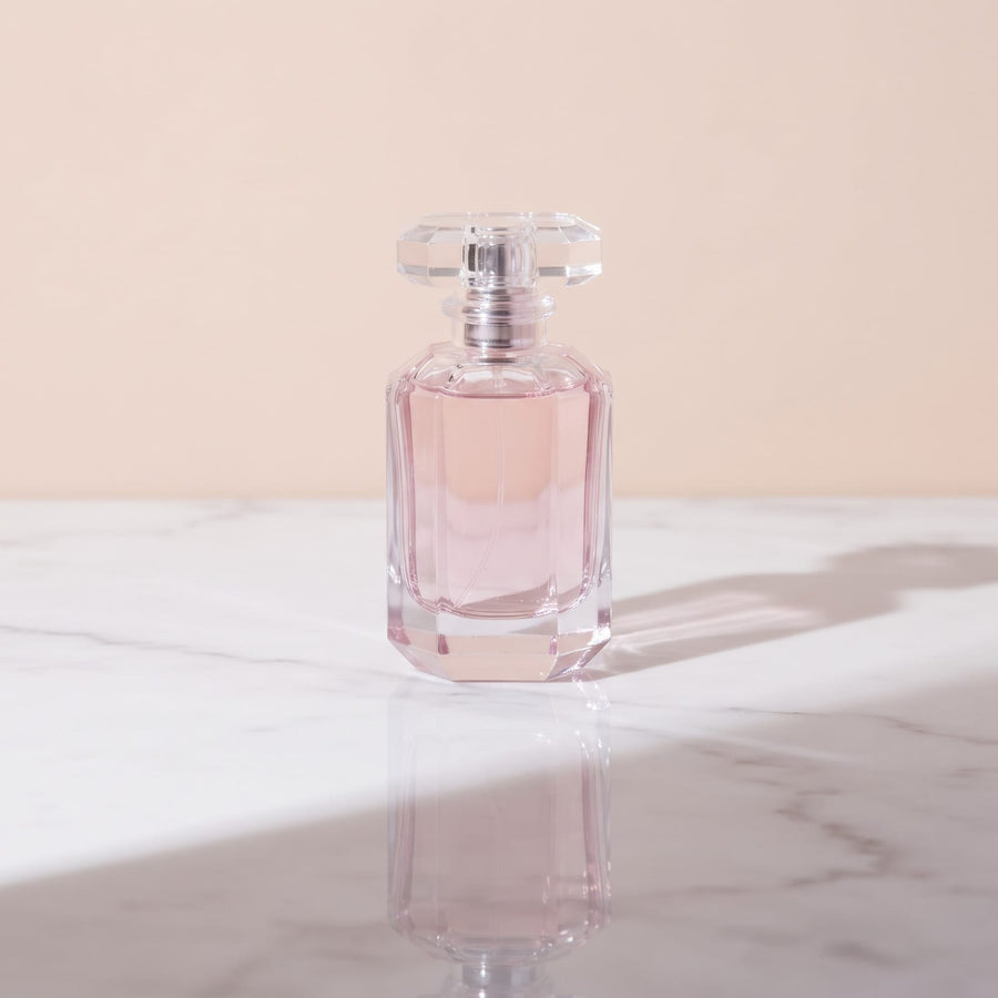 Sacred Pause Extrait de Parfum, faceted pink glass bottle with a crystal cap on white marble